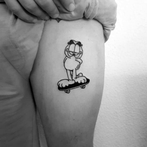 Minimalist black and white Garfield tattoo standing confidently on a skateboard—simple yet stylish design with a cool vibe.