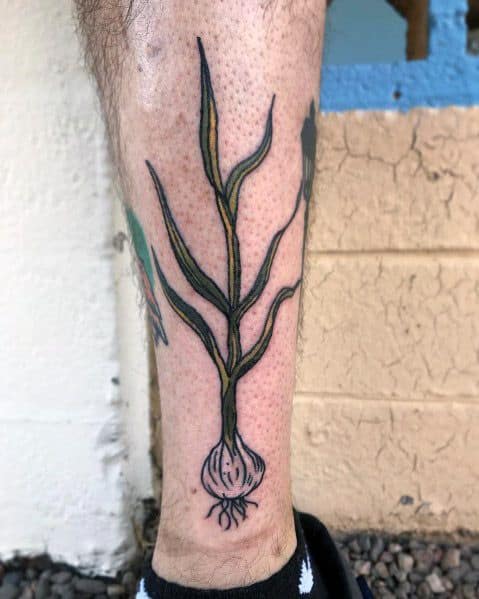 Minimalist garlic tattoo with long, flowing green stems and fine linework, creating a natural and organic botanical design on the leg.