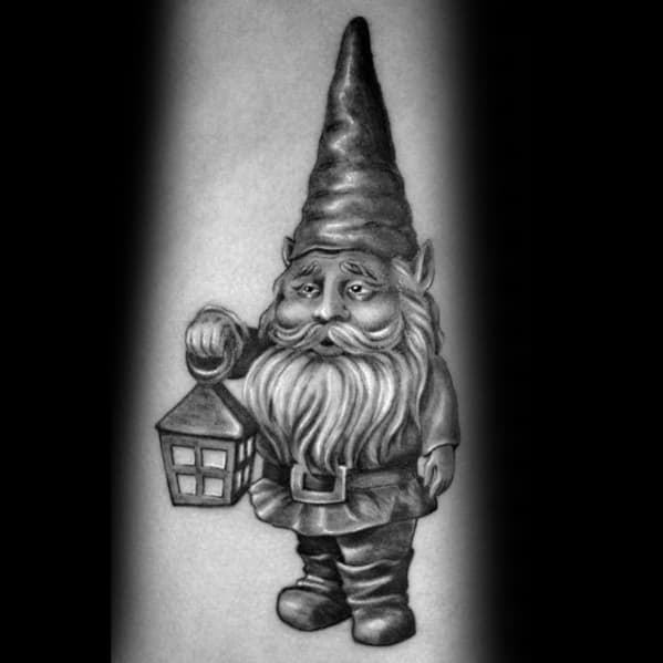 Black and gray tattoo of a solemn gnome with a tall hat and long beard, holding a lantern, standing in a classic pose with detailed shading.