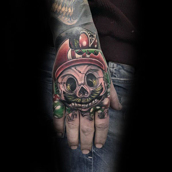 Dark and eerie *Super Mario* tattoo featuring a skeletal Mario with hollow eyes and sinister shading, creating a haunting and surreal design on the hand.
