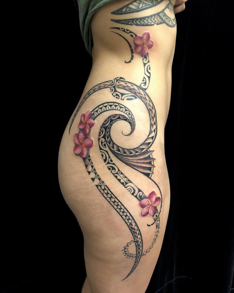 Curved tribal tattoo with red plumeria flowers on a person's side