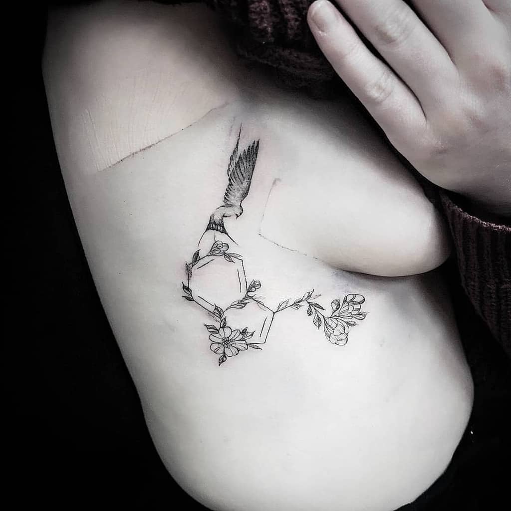 Serotonin molecule tattoo on the side with flowers and a bird, symbolizing freedom and natural beauty