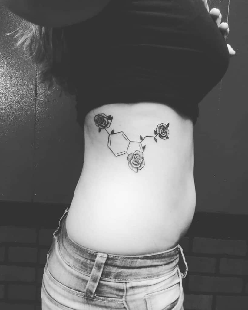 Serotonin molecule tattoo on the side, adorned with three roses at key points for a feminine touch.