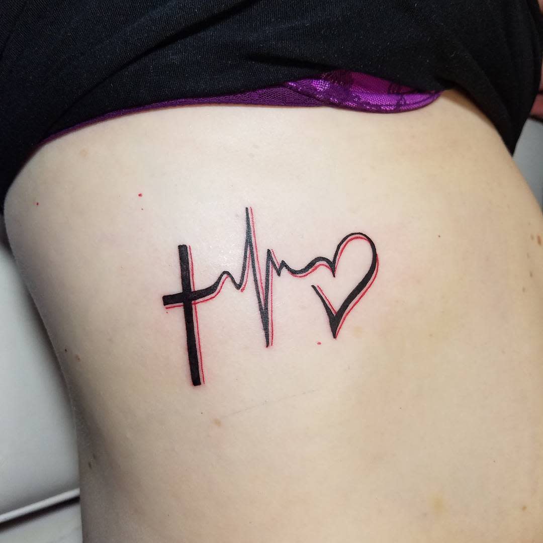 Tattoo of a cross entwined with a heartbeat line and heart symbol, embodying faith and love on the skin