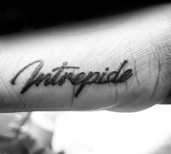 Side hand tattoo for men with the word intrépide in elegant cursive script, meaning fearless in French.