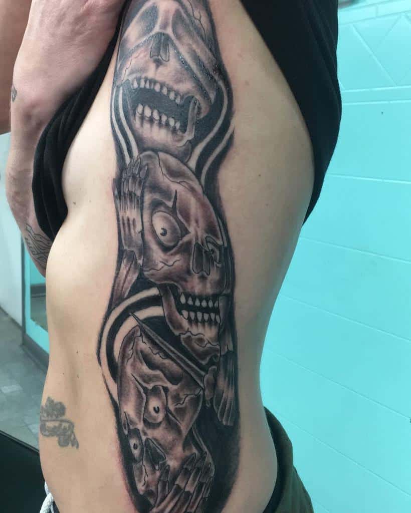 Tattoo of three skulls on a man's side, each covering ears, eyes, and mouth in "see no evil" style