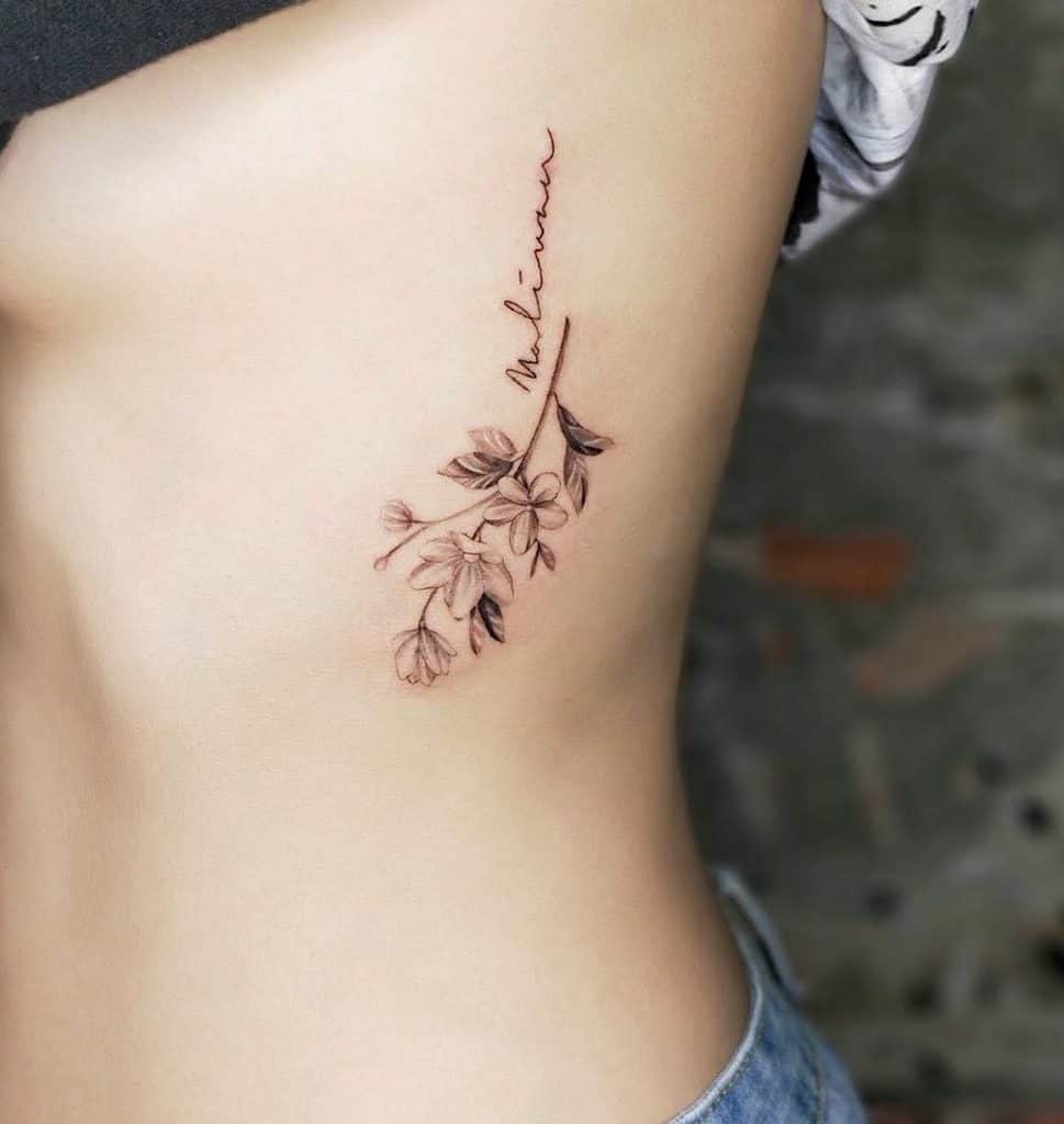 Side tattoo of Jasminee flowers and the word "Melissa" on a ribcage