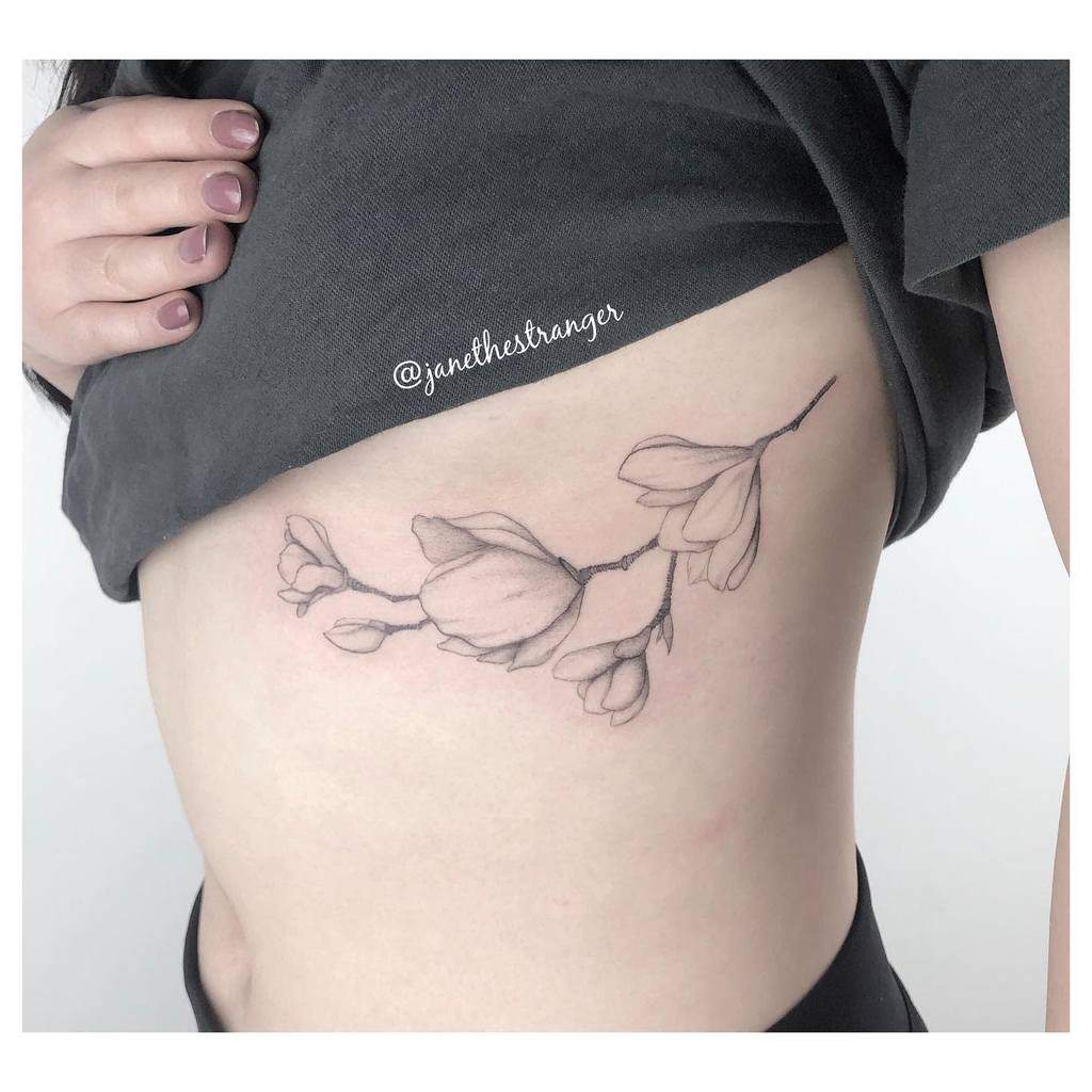 A magnolia tattoo gracefully adorns a person's side