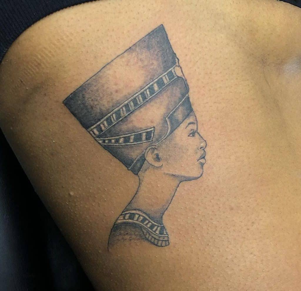Delicate side-profile tattoo of Queen Nefertiti captures her elegance and royal stature with fine shading, showcasing the intricate details of her iconic headdress and neckpiece
