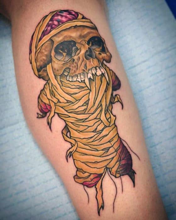 Colorful tattoo of a wrapped mummy skull with exposed brain, inspired by Metallica’s Damage, Inc. artwork in a bold, cartoonish style.