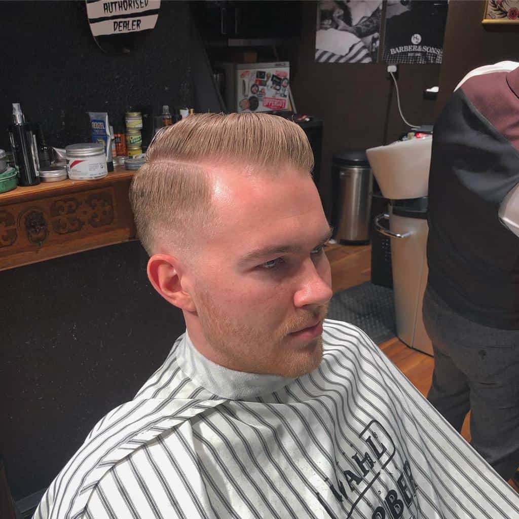 A peaky blinder haircut variation with a side-part on top paired with tapered sides