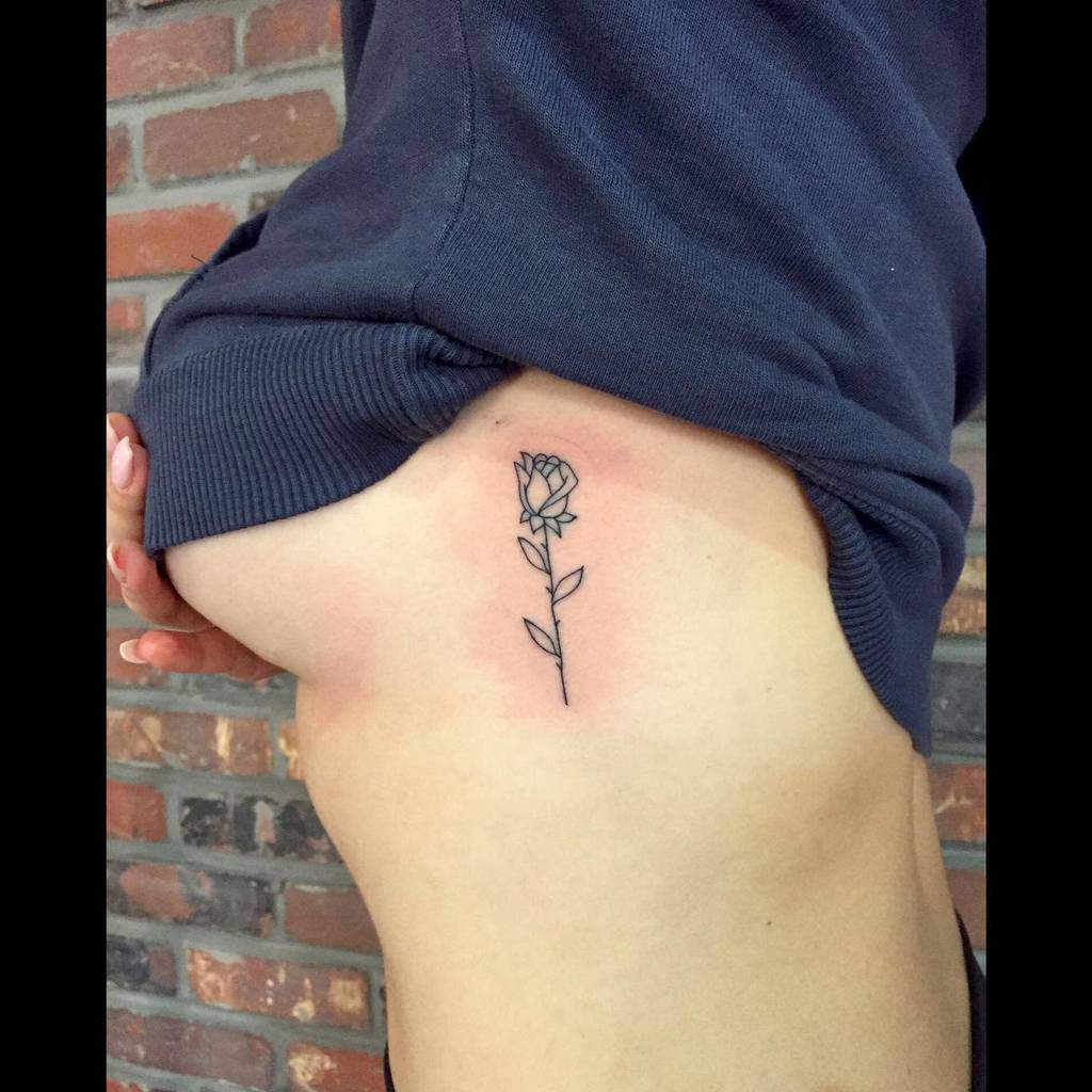 Minimalist rose tattoo on a person's ribcage