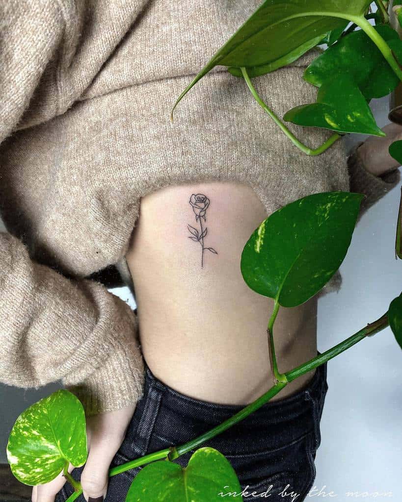 Delicate rose tattoo on a person's ribcage