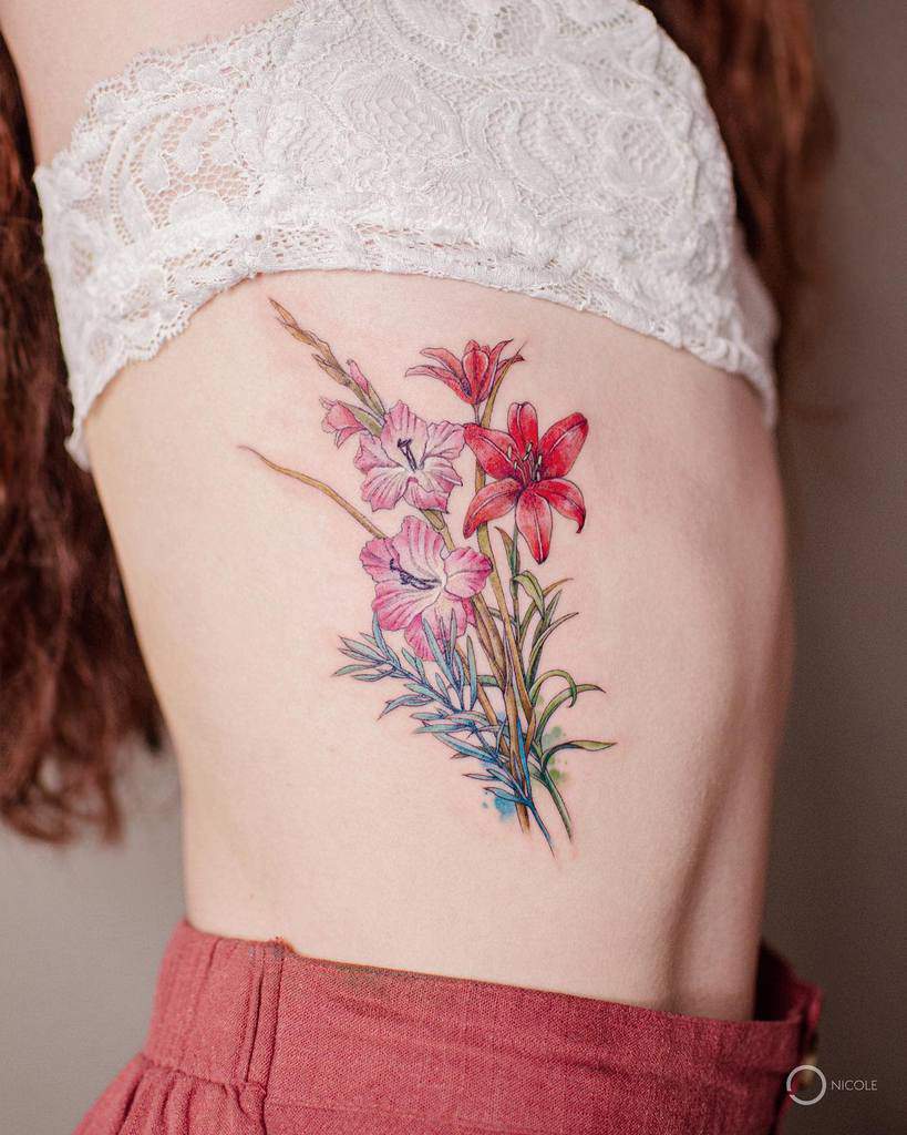 Floral tattoo on a woman's ribcage featuring pink and red flowers with green leaves