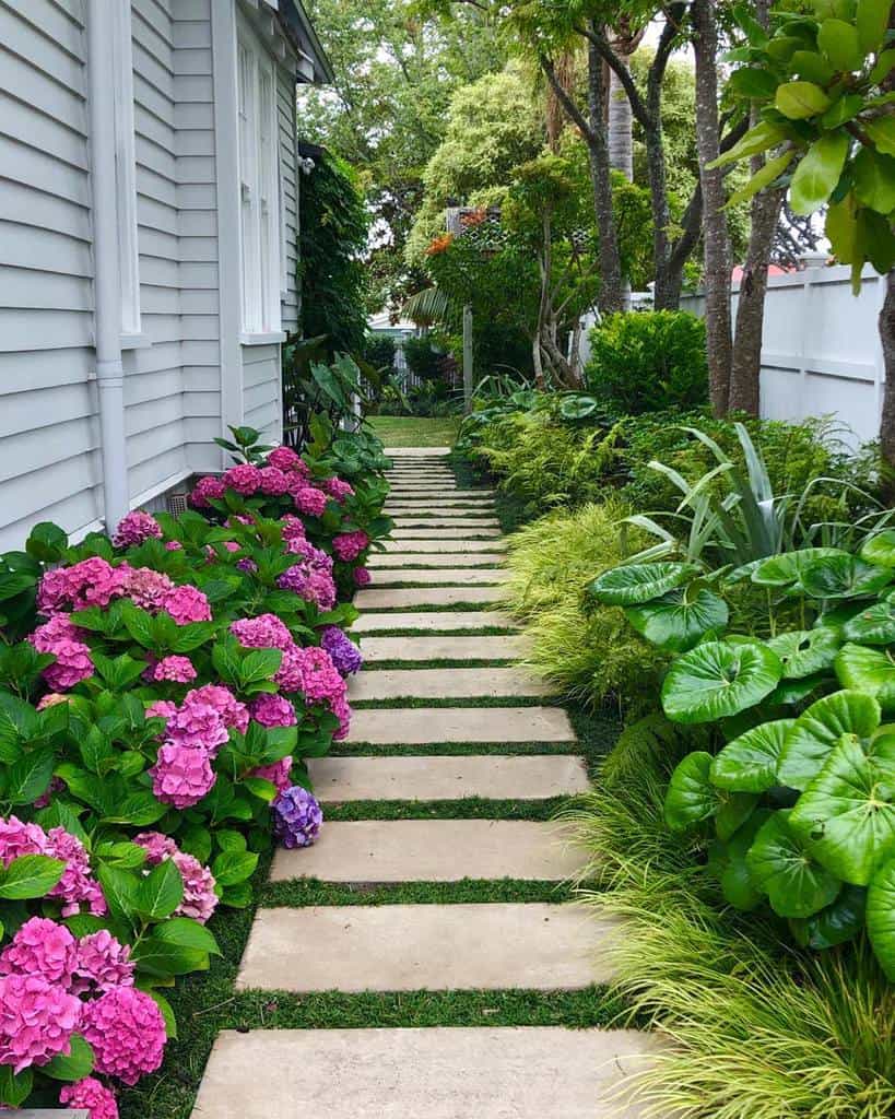 side yard garden with paved pathway with purple flowers