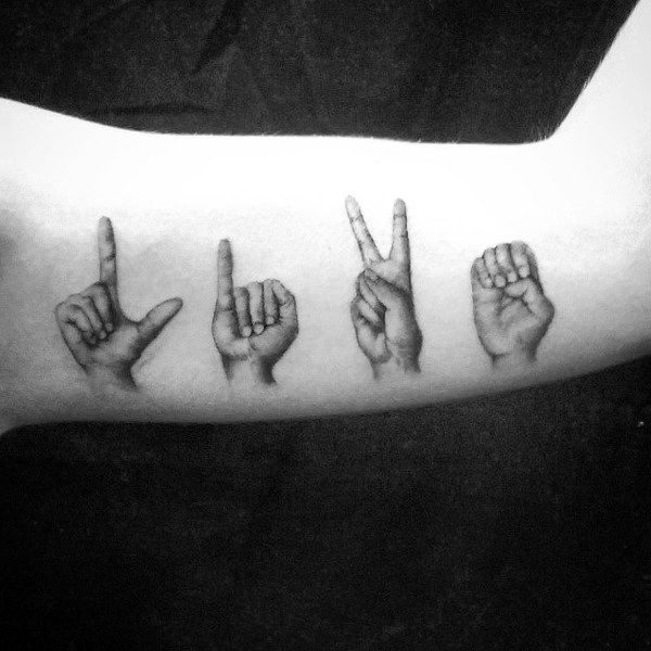realistic black and grey tattoo of hands spelling "LOVE" in American Sign Language, placed along the inner arm with detailed shading