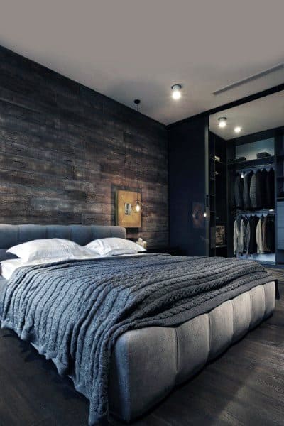 Modern bedroom with a dark textured accent wall, grey bedding, and an open closet with hanging clothes