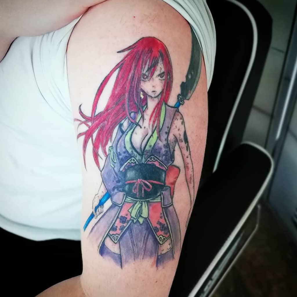 Colorful tattoo of Erza Scarlet from Fairy Tail on the upper arm, featuring her Samurai armor, flowing red hair, and a fierce battle-ready expression.