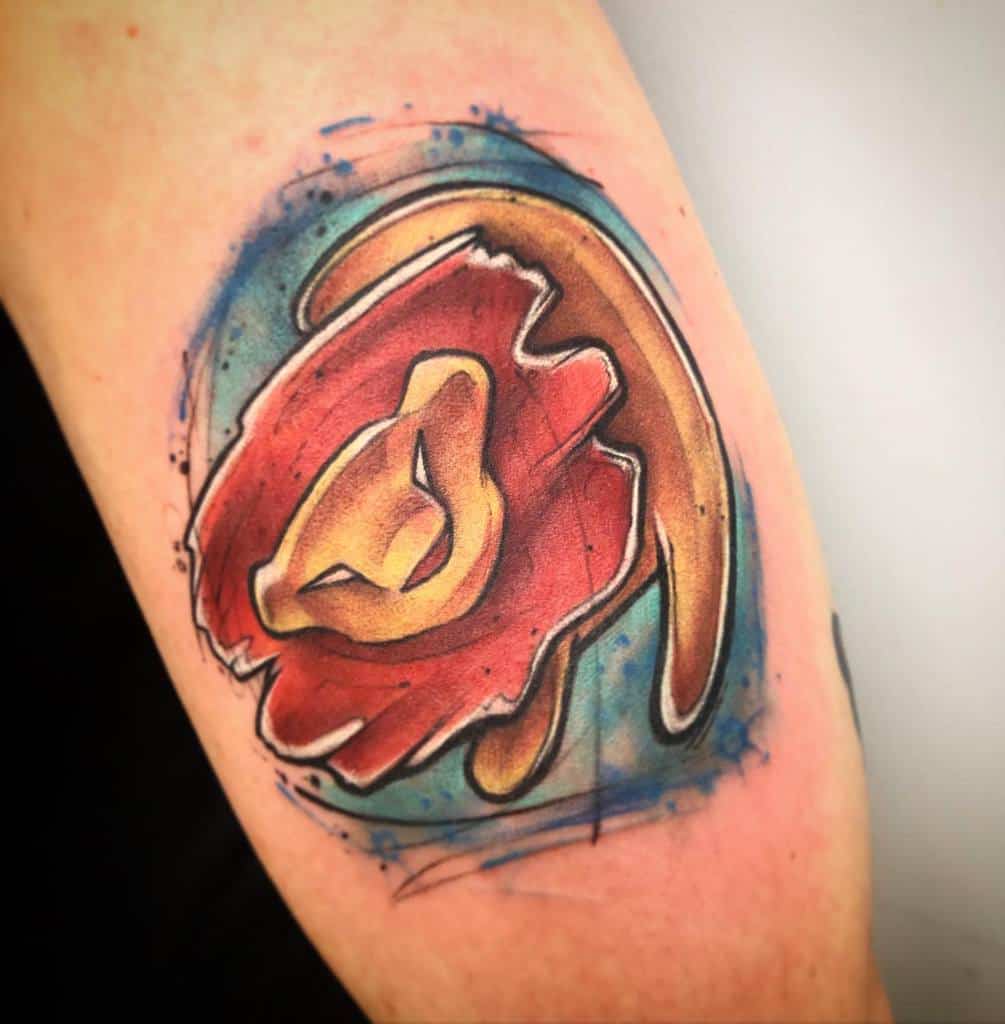 Vibrant watercolor tattoo of Simba in a dynamic pose, surrounded by a burst of red and blue tones