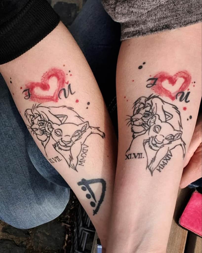 Two arms with matching tattoos featuring Simba and Nala, red heart symbols, date in Roman numerals, and musical note