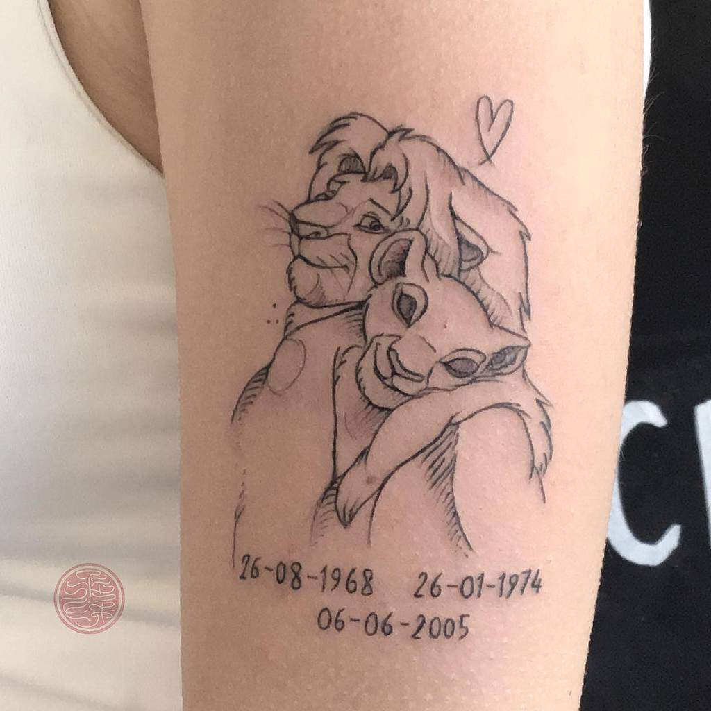 Minimalistic tattoo of Simba and Mufasa hugging, with the dates 26-08-1968, 26-01-1974, and 06-06-2005 beneath, accompanied by a heart symbol