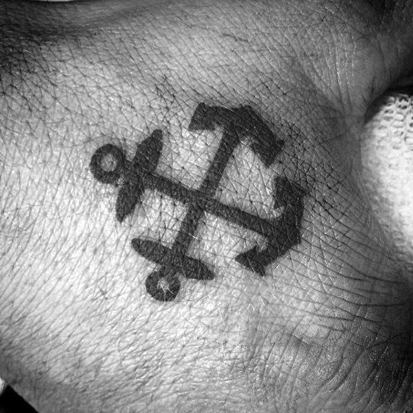 Bold black double anchor tattoo on the hand, featuring a symmetrical design that symbolizes strength, stability, and a deep maritime connection.