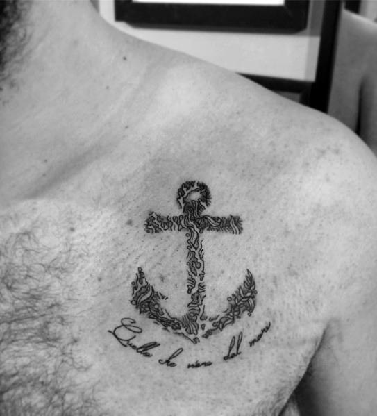 Intricate black anchor tattoo on the chest, composed of fine script-like details, paired with a cursive phrase, symbolizing strength and resilience.