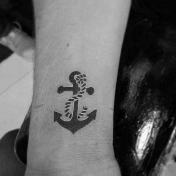 Small black anchor tattoo on the wrist with a wrapped rope, featuring a bold and simple design that symbolizes strength, stability, and resilience.