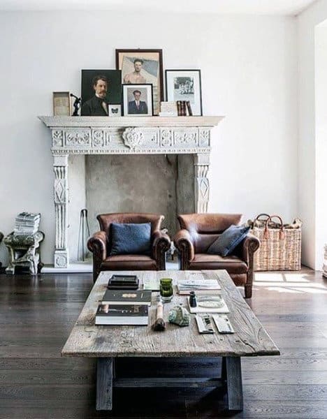 Vintage living room with leather armchairs, rustic fireplace, and wooden coffee table.