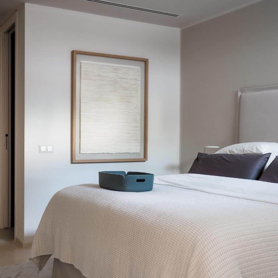 Minimalist basement bedroom with neutral tones, simple wall art, and a cozy bed setup.