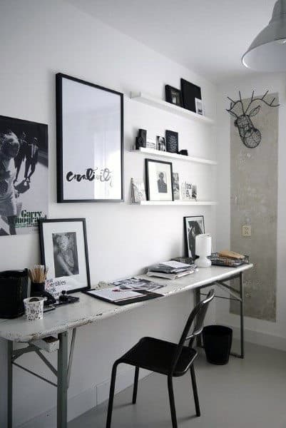 Minimalist workspace with a long desk, chair, framed art on the wall, and shelves with decor