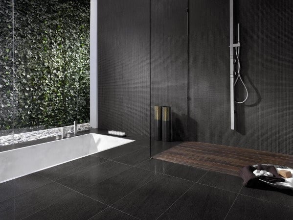 Modern bathroom with a bathtub, shower, dark tiles, and a wall covered in plants