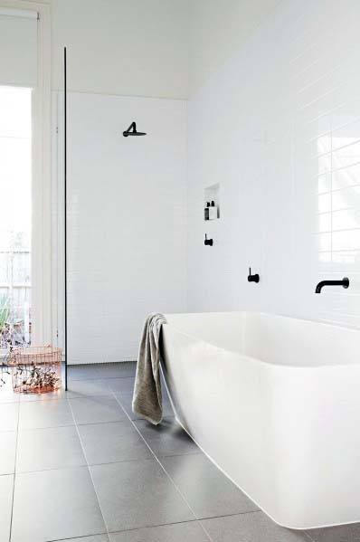 Minimalist bathroom with a white tub, black fixtures, and a crisp towel draped over the tub's edge