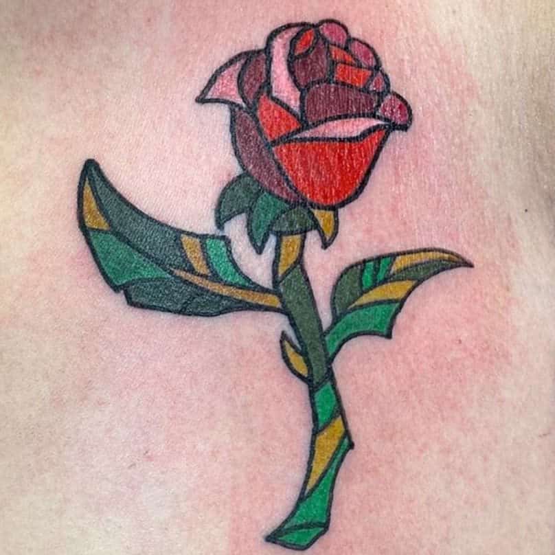 Tattoo of a red rose with green leaves on skin