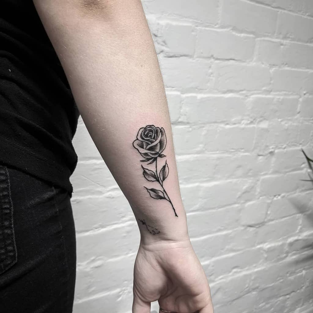 A delicate black and white rose tattoo graces a forearm