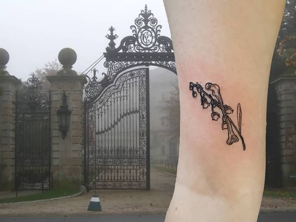 Minimalist black ink Lily of the Valley tattoo, featuring fine-line floral details