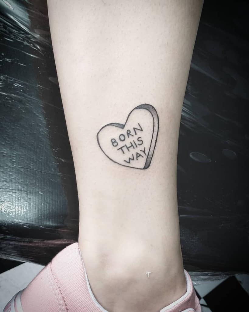 Heart-shaped tattoo on a leg with the words "Born This Way" 