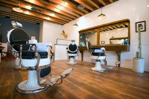Rustic barbershop with vintage chairs, wooden floors, and white tiled walls.