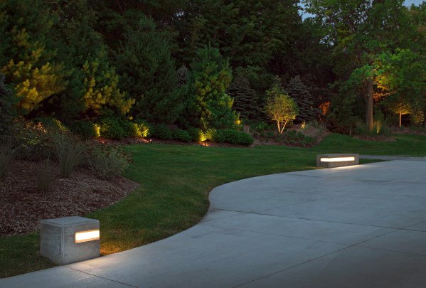 Contemporary driveway with minimalistic block lighting along the edges, gently illuminating the path and surrounding greenery