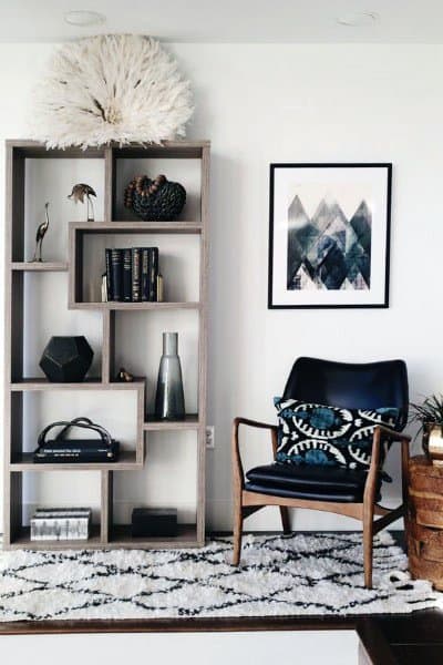 Modern living room with a geometric shelf, books, decor items, a framed abstract picture, and a wooden chair