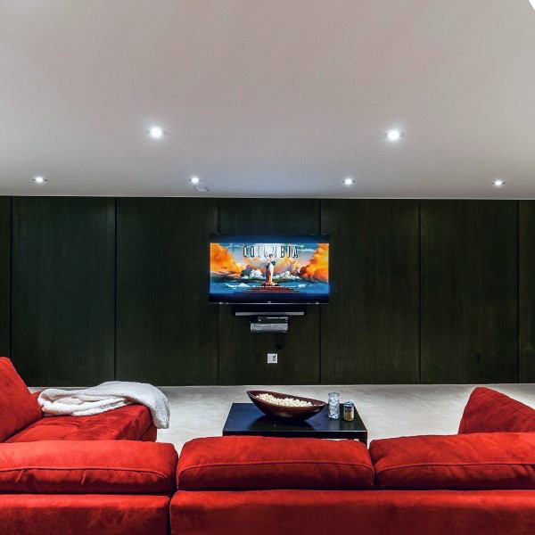 Basement home theater with drywall ceiling, recessed lighting, and vibrant red sectional sofa.