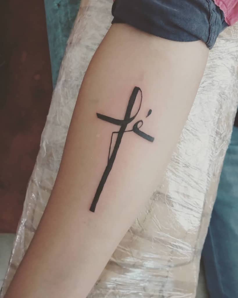 Tattoo of an abstract cross symbolizing faith with the word "fé" elegantly inked on a person's arm