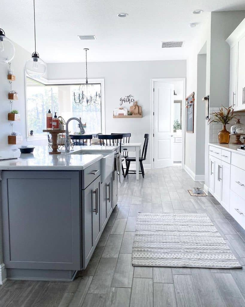 simple farmhouse kitchen white cabinets gray island with marble countertop white wood table with black chairs chandelier