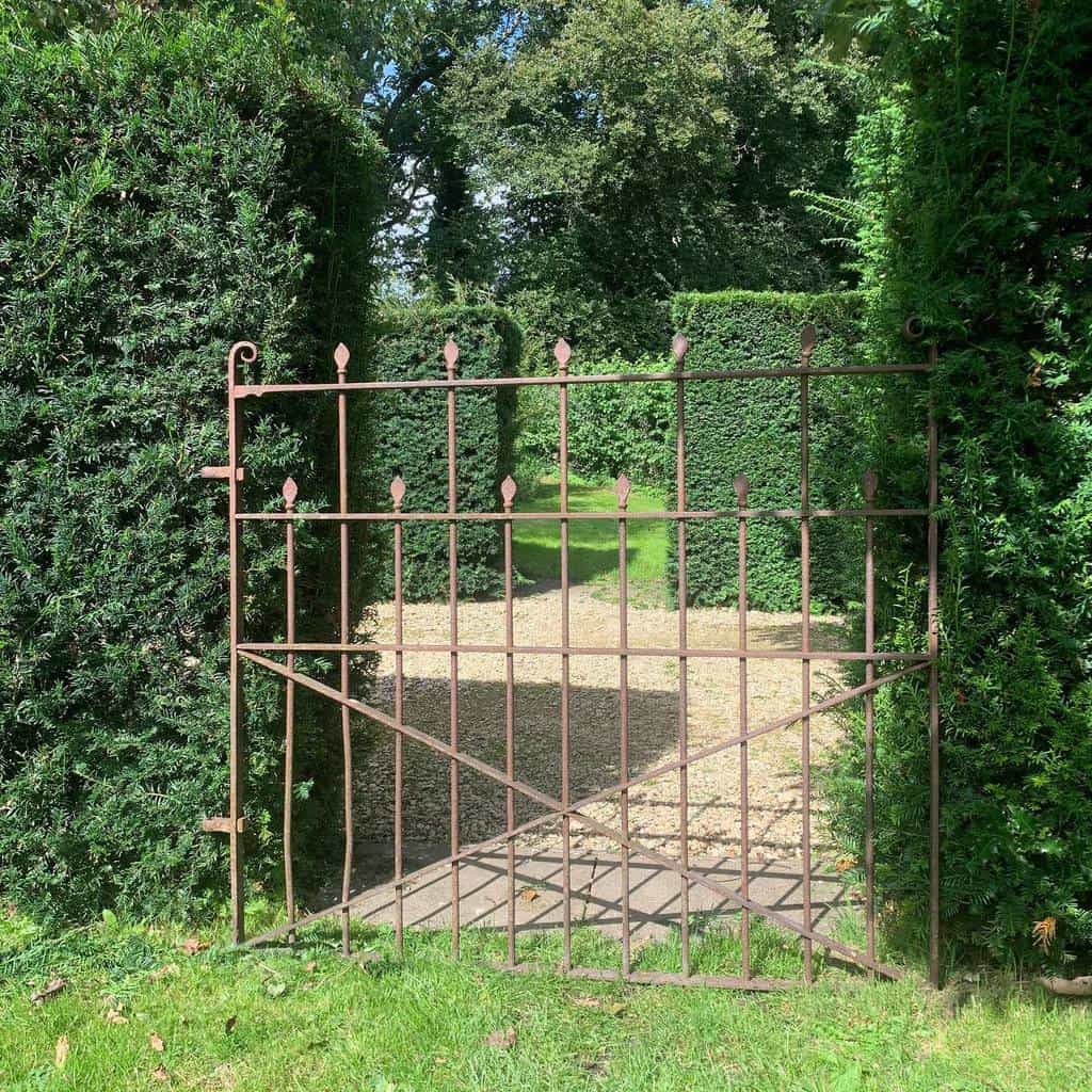 simple cast iron garden gate large green hedges