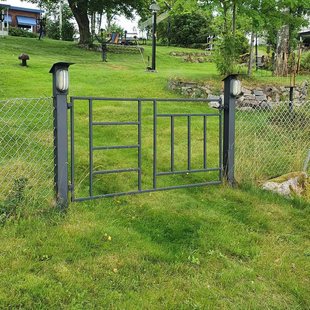 simple metal garden gate with lights and wire fence