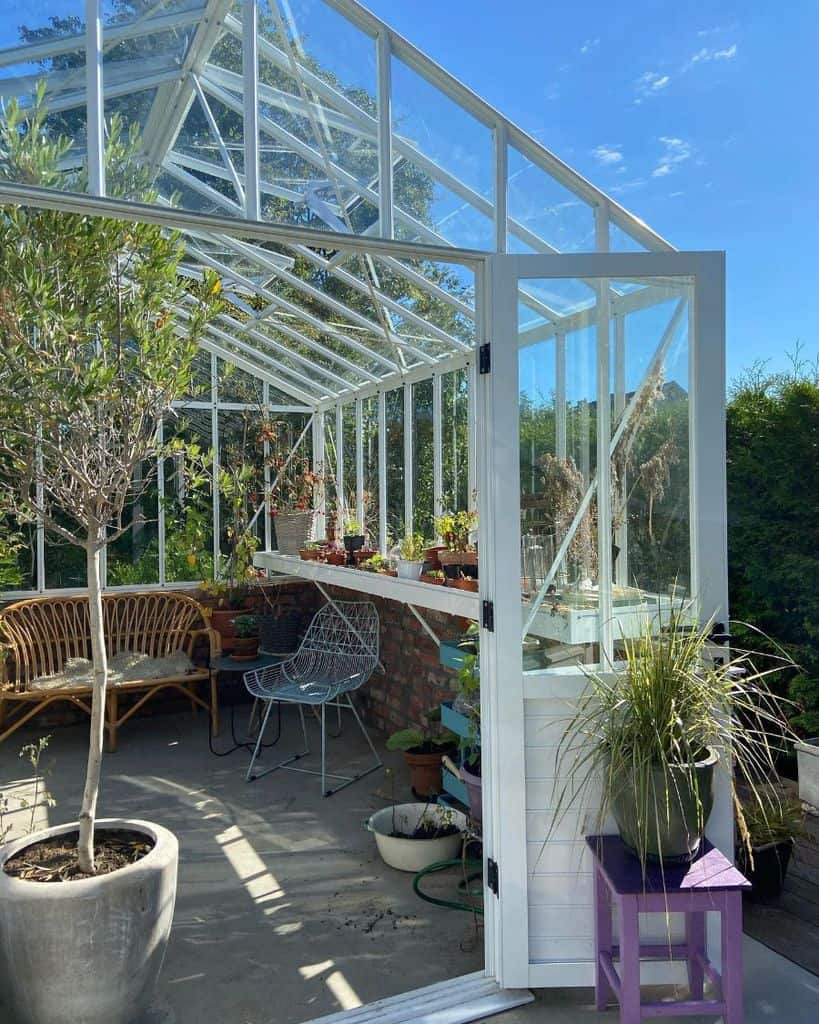 simple white frame greenhouse seats concrete floor