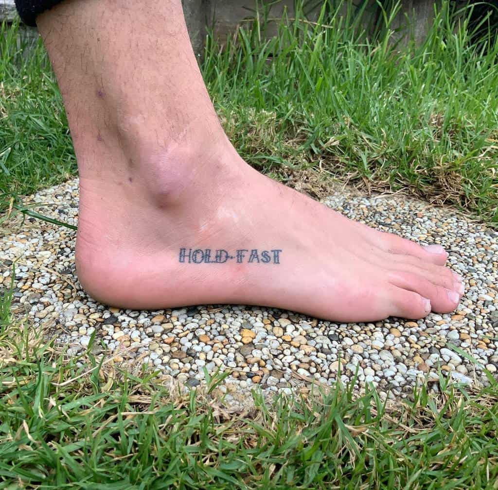 Foot tattooed with "HOLD FAST" near ankle