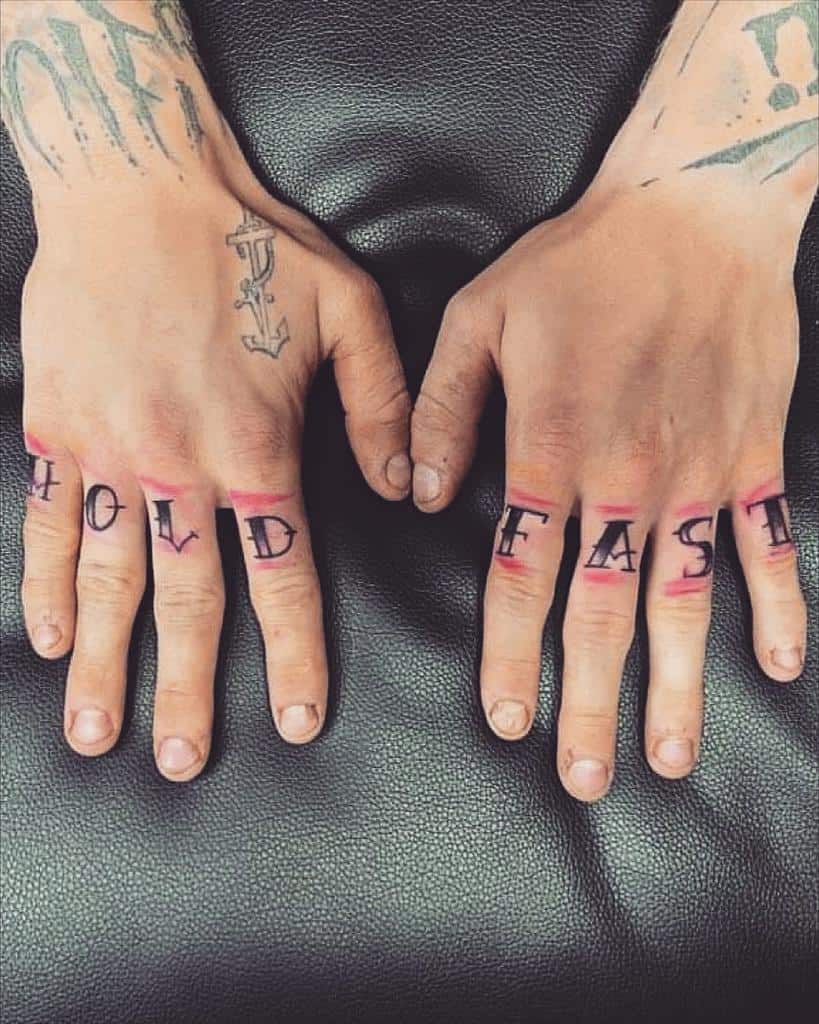 Hands with "HOLD FAST" tattooed on knuckles