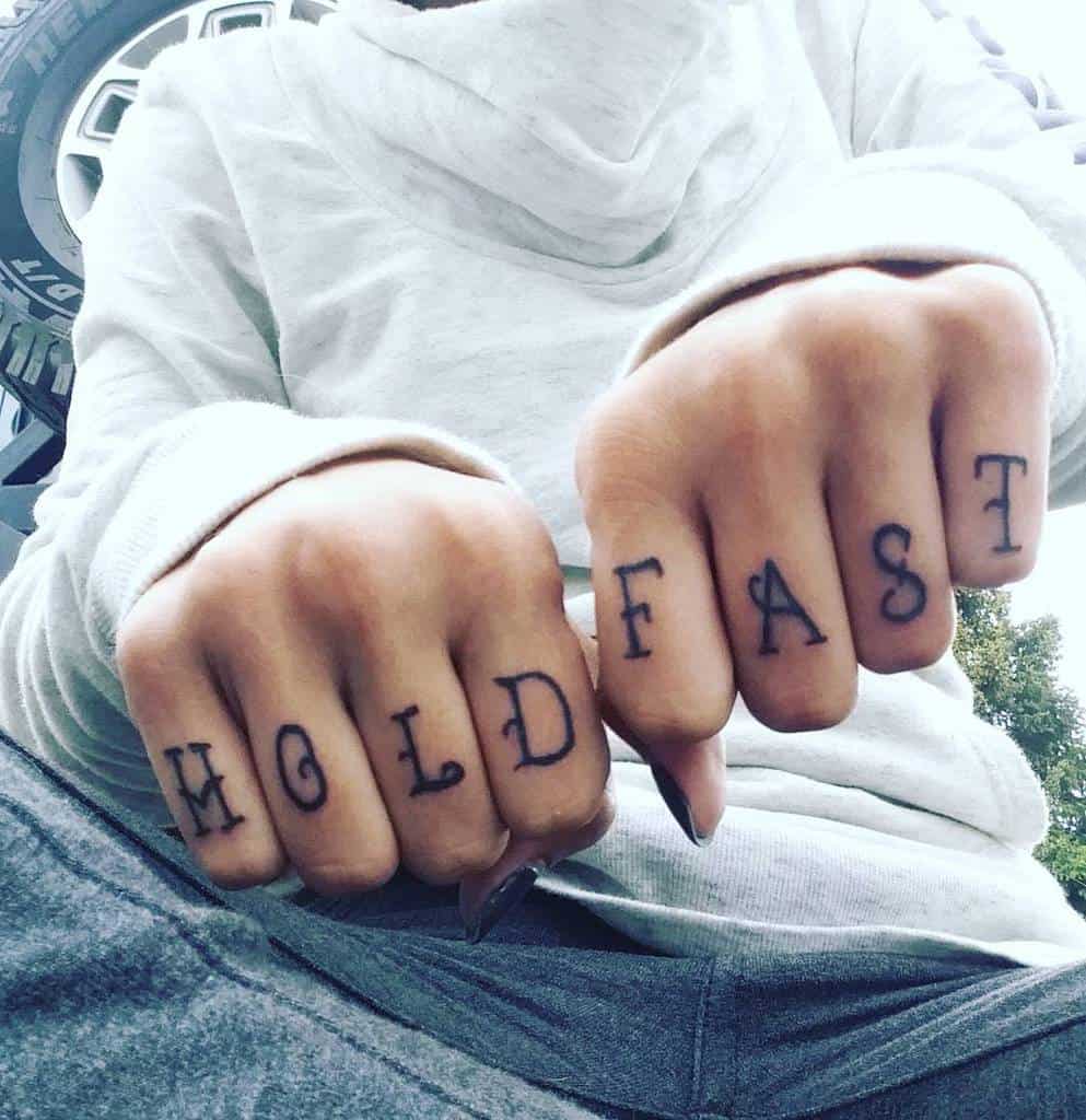 Person with "HOLD FAST" tattoos on their knuckles