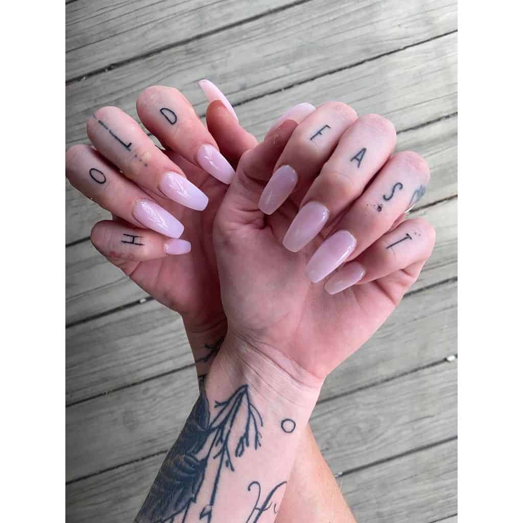 Minimalistic 'Hold Fast' tattoos inked across the fingers